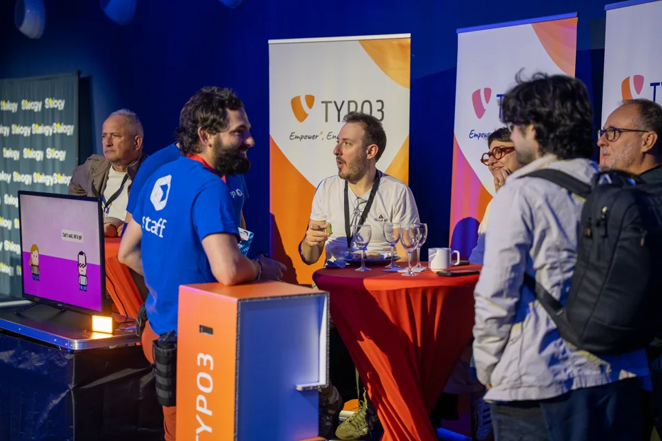 Des participants et un membre du staff échangent autour d’une table sur le stand TYPO3 au Forum PHP 2026