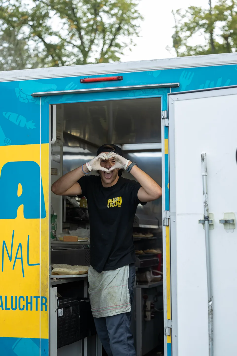 Une personne forme un cœur avec ses mains dans l’encadrement de son food truck
